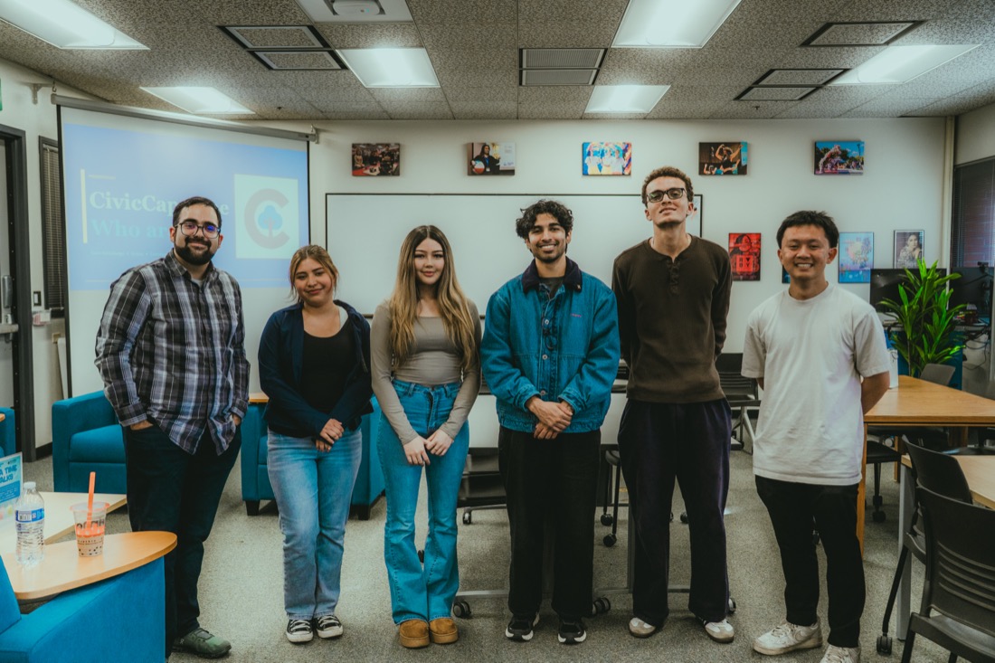 Six CivicCapstone fellows and staff standing in a row in a classroom, with a CivicCapstone slide projected behind them